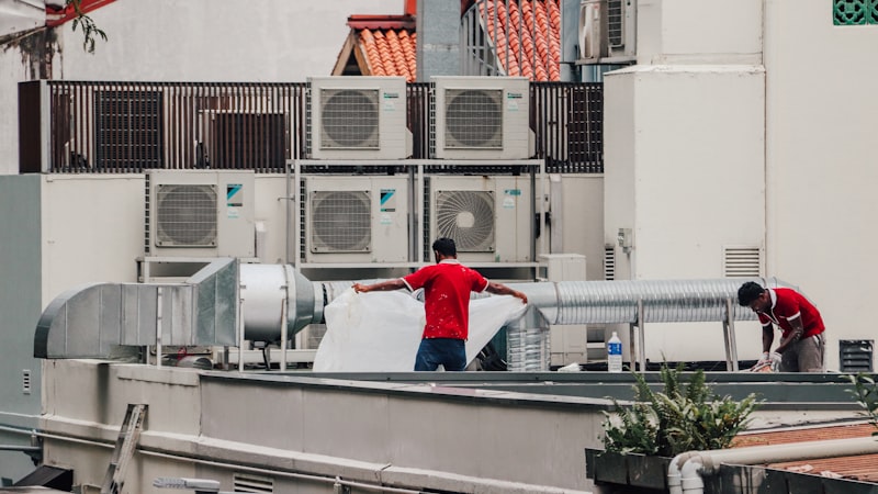 Two technicians working among rooftop air conditioning units